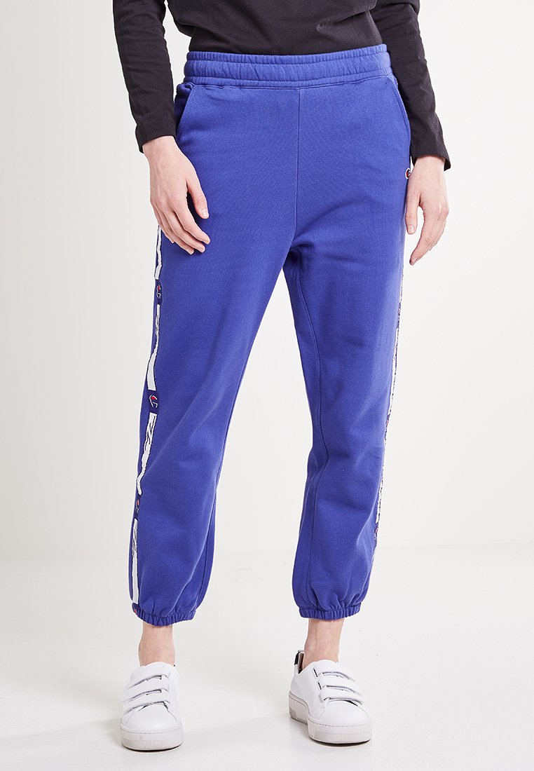 Blauwe katoenen joggers met een elastische tailleband en manchetten, met witte zijstrepen en logoaccenten. Glad textuur en taps toelopende pasvorm.