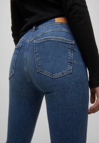 Blauwe denim skinny jeans met een middelhoge taille, voorzien van twee achterzakken en een tan leren patch op de tailleband.