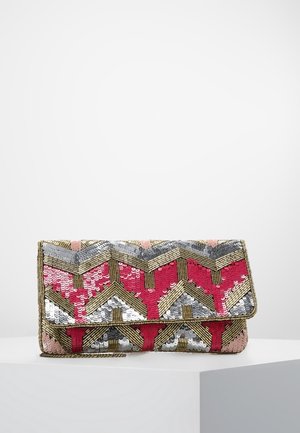 Pochette avec motif chevron composée de sequins roses, dorés, argentés et blancs, posée sur un socle blanc devant un fond uni.