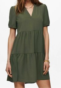 Robe verte à volants avec manches courtes bouffantes, décolleté en V et tissu doux. La robe présente des ourlets à volants et une silhouette décontractée.