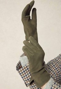 Olive green gloves made of soft suede, featuring a snug fit and elegant design. The accenting outfit has a checkered pattern.