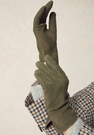 Olive green gloves made of soft suede, featuring a snug fit and elegant design. The accenting outfit has a checkered pattern.