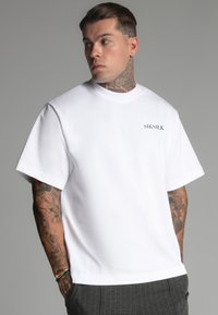 Fehér, rövid ujjú póló kerek nyakkivágással. Bal mellrészen egy kis fekete SIKSILK logóval ellátott. Simább anyagból készült.
