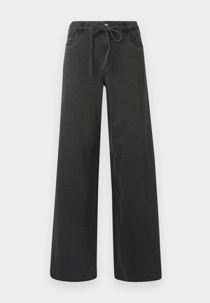 Mustad laiad teksapüksid, mis on valmistatud denimist, kummiga vöökoht, kaks esikotid ja sile tekstuur. Pole nähtavaid mustreid ega aktsente.