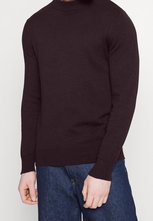 Ciemnobrązowy sweter z długim rękawem, z prążkowanym dekoltem i mankietami, uszyty z miękkiego dzianiny, w połączeniu z niebieskimi dżinsami.