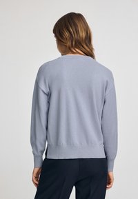 Pull bleu clair à manches longues, avec un col rond et des poignets et un ourlet côtelés. Texture douce, coupe décontractée, conçu pour un port décontracté.