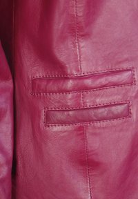 Fuchsia Lederjacke mit glatter Textur, sichtbaren Nähten und zwei horizontalen Taschen. Nahaufnahme der Taschendetails.
