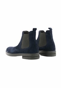 Stivaletti Chelsea in suede blu navy con pannelli laterali elasticizzati, punta arrotondata e suola in gomma nera. Finitura testurizzata e linguette per una facile calzata.