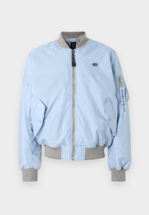 Hellblaue Bomberjacke mit grauem, geripptem Kragen, Bündchen und Saum, Frontreißverschluss, Pattentaschen und Reißverschlusstasche am Ärmel mit "Remove Before Flight"-Anhänger.