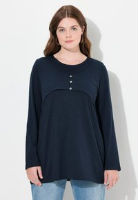 Langärmliges navyblaues Oberteil mit rundem Ausschnitt und drei dekorativen Knöpfen an der Brust, aus weichem, strukturiertem Stoff.