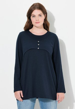 Maglietta a maniche lunghe di colore blu navy con scollo rotondo e tre bottoni decorativi sul petto, realizzata in un morbido tessuto testurizzato.