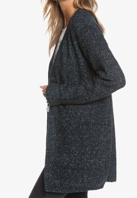 Lang, åben-front cardigan i mørkeblå med et tekstureret strikkemønster. Har lange ærmer og en afslappet pasform. Velegnet til layering.
