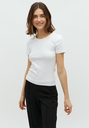 Camiseta blanca de manga corta fabricada en tela acanalada, con cuello redondo y un corte ajustado, combinada con pantalones negros.