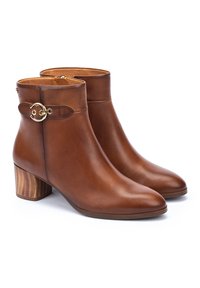 Botas de tobillo de cuero marrón con punta afilada, tacón bajo en bloque y detalles en dorado. Textura suave con un diseño elegante.