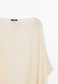 Fløjlsbluse i cremefarve med bred bådhalsudskæring, korte flagrende ærmer og en Massimo Dutti-etiket bag på kraven.