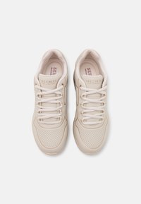 Beige athletic shoes made of synthetic material, featuring lace-up design, perforated accents on the toe box, and a padded collar for comfort.