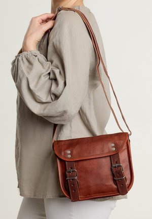 Sac en cuir brun à bandoulière avec rabat, matériel en argent et bande réglable. Surface texturée avec des accents de boucle à l'avant.