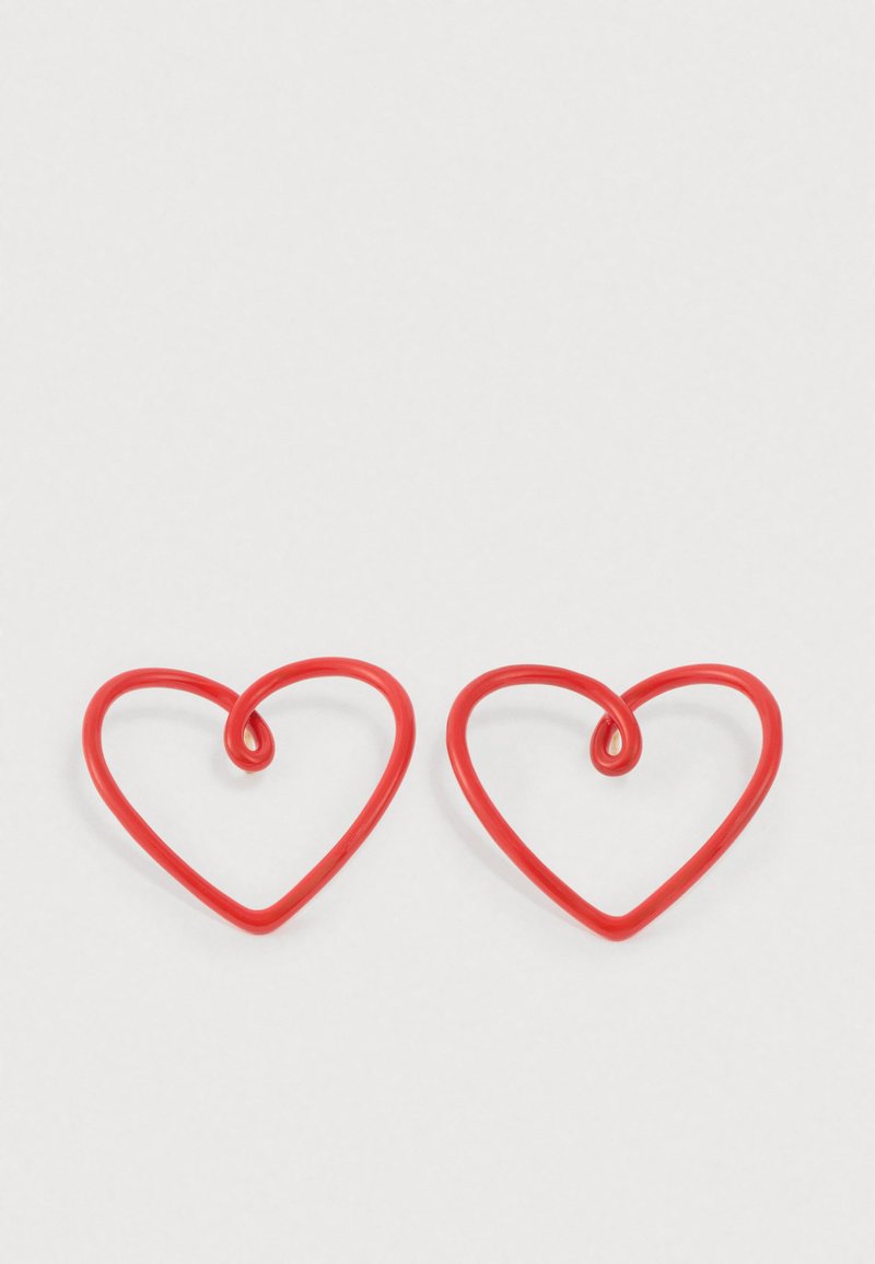 Červené náušnice v tvare srdca vyrobené z flexibilného materiálu, s kudrlinkovým akcentom na hornom strede každého srdca.