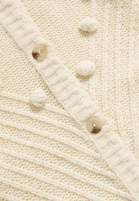 Cremfarbener Strickcardigan mit einem strukturierten Muster, bobbelartigen Akzenten und einer gerippten Knopfblende mit großen, hellen Knöpfen.