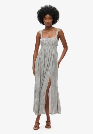 Robe maxi à imprimé noir et blanc. Présente un buste cintré, des bretelles larges et une fente frontale jusqu'à la cuisse. Tissu léger avec une texture fluide.