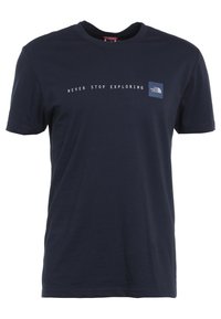 Tummansininen puuvillapaita, jossa on pyöreä pääntie, lyhyet hihat ja valkoinen teksti, joka sanoo "ÄLÄ KOSKAAN PYSÄHDY TUTKIMAAN" logon yläpuolella.