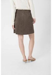Bruine corduroy rok met een rechte snit, voorzien van een middellange taille en subtiele achternaad. Gekocht met een lichtgekleurde top en sandalen.