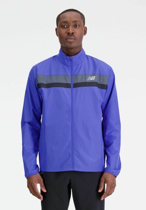 Chaqueta ligera de color púrpura con un alto cuello, que presenta rayas horizontales en gris y negro en el pecho y un cierre frontal con cremallera.