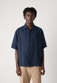 Marineblå kortermet skjorte med knapper i lett stoff, som har en avslappet passform, myk tekstur og en klassisk krage med knapper.