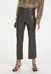 Hochtaillierte, dunkelgraue Kunstlederhosen mit einem eleganten, körperbetonten Schnitt und gekürzten, ausgestellten Beinen, kombiniert mit einer Bluse im Leopardenmuster.
