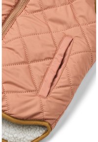 Ružičasta jakna s quilted dizajnom i glatkom vanjštinom, koja ima bočnu džep, kontrastne smeđe obrube i mekanu bijelu flis podstavu oko ovratnika.