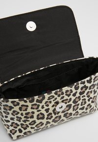 Torebka z faux skóry w leopardzie wzór, beżowa i czarna, z metalowym zapięciem. Wnętrze z czarną podszewką i wieloma przegrodami.