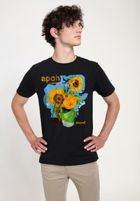 Černé bavlněné tričko s barevným grafickým motivem slunečnice a textem. Design zahrnuje zelenou vázu, modré pozadí a odkaz na umělce.