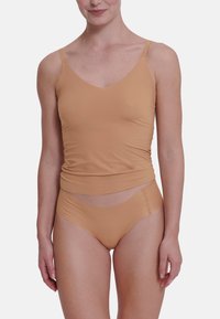 Nude top met spaghettibandjes en geplooide structuur, gecombineerd met bijpassende hooggeknipte slips met een gebogen uitsnijding.