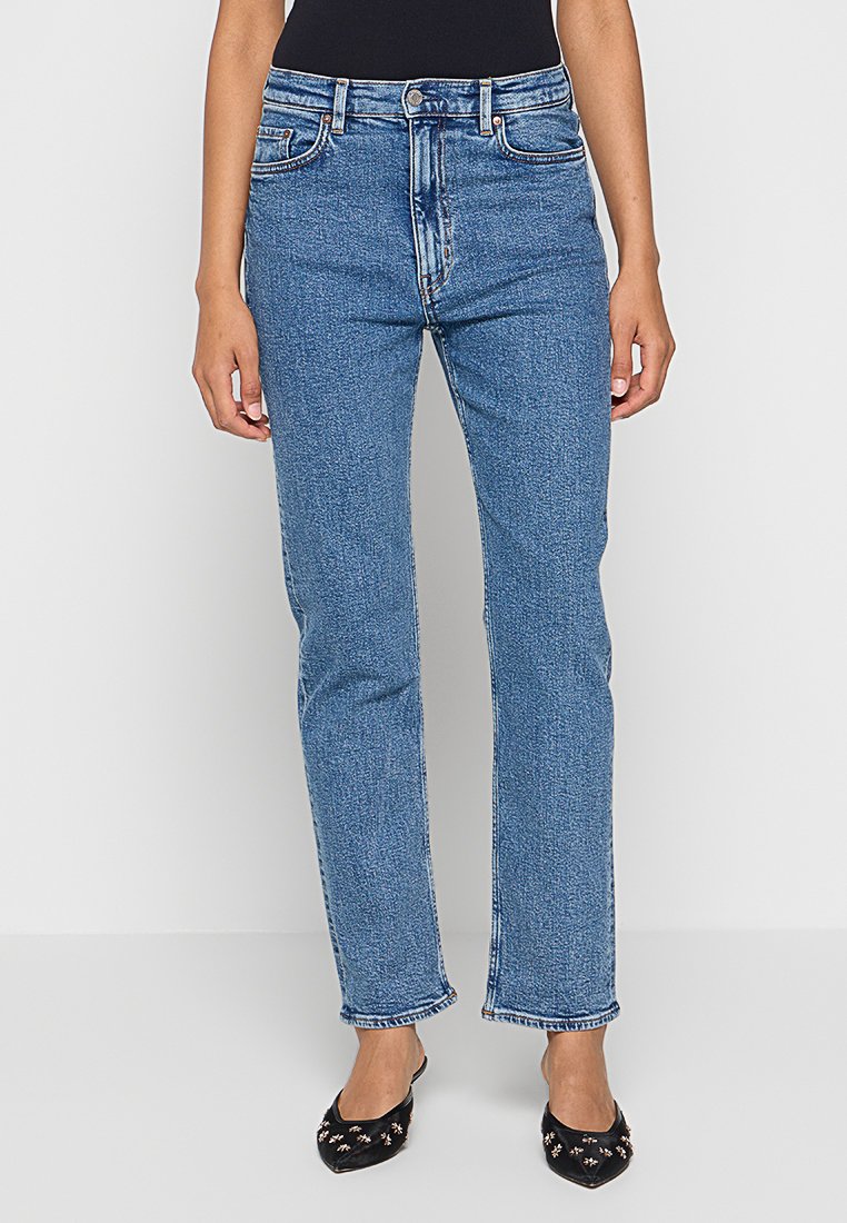 Blaue Denim-Jeans mit geradem Bein, hoher Taille und dezenten Stickdetails. Der Stoff hat eine leichte Textur und einen gleichmäßigen Farbton.