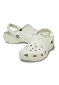 Zuecos blancos impermeables hechos de material sintético, con orificios de ventilación, una correa trasera y suelas texturizadas para mayor agarre.