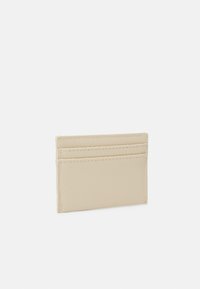 Leather cardholder in light beige, featuring a textured surface, slim design with three card slots on one side, and neat stitching.