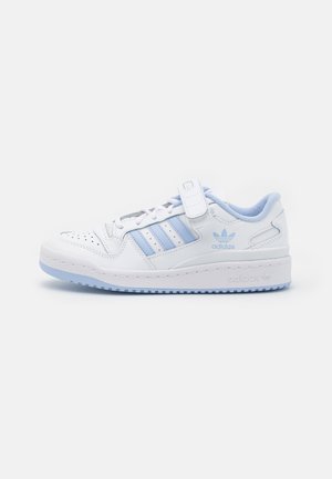 White Adidas sneaker with light blue accents, three stripes, perforated toe, velcro strap, and rubber sole on a plain background.