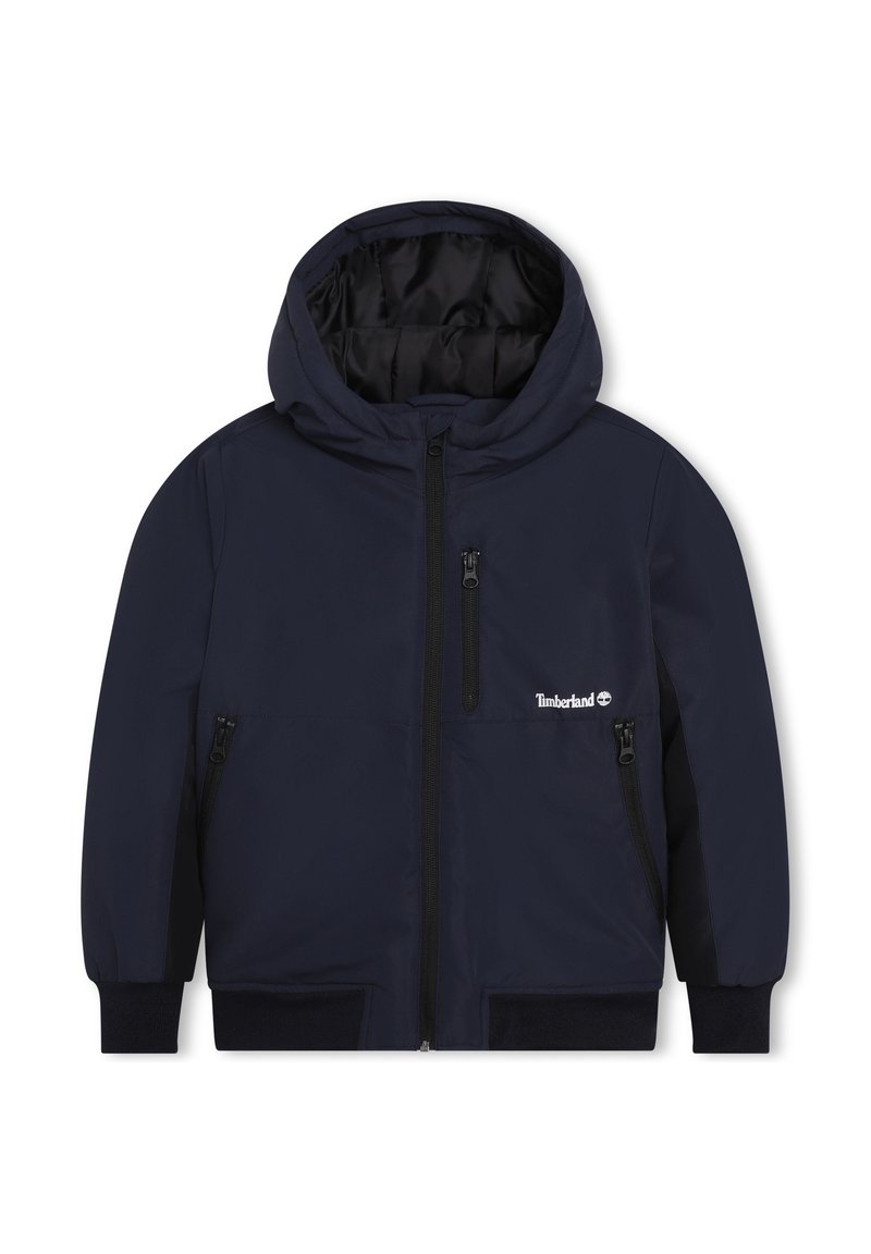 Námořnická modrá bunda s kapucí, s předním zipem, dvěma bočními kapsami na zip a vnitřním podšíváním. Obsahuje logo Timberland na levé hrudi.
