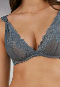 Grå spets-bustier med V-ringad design, prydd med blommönster och mesh-textur. Justerbara axelband ökar komforten och passformen.