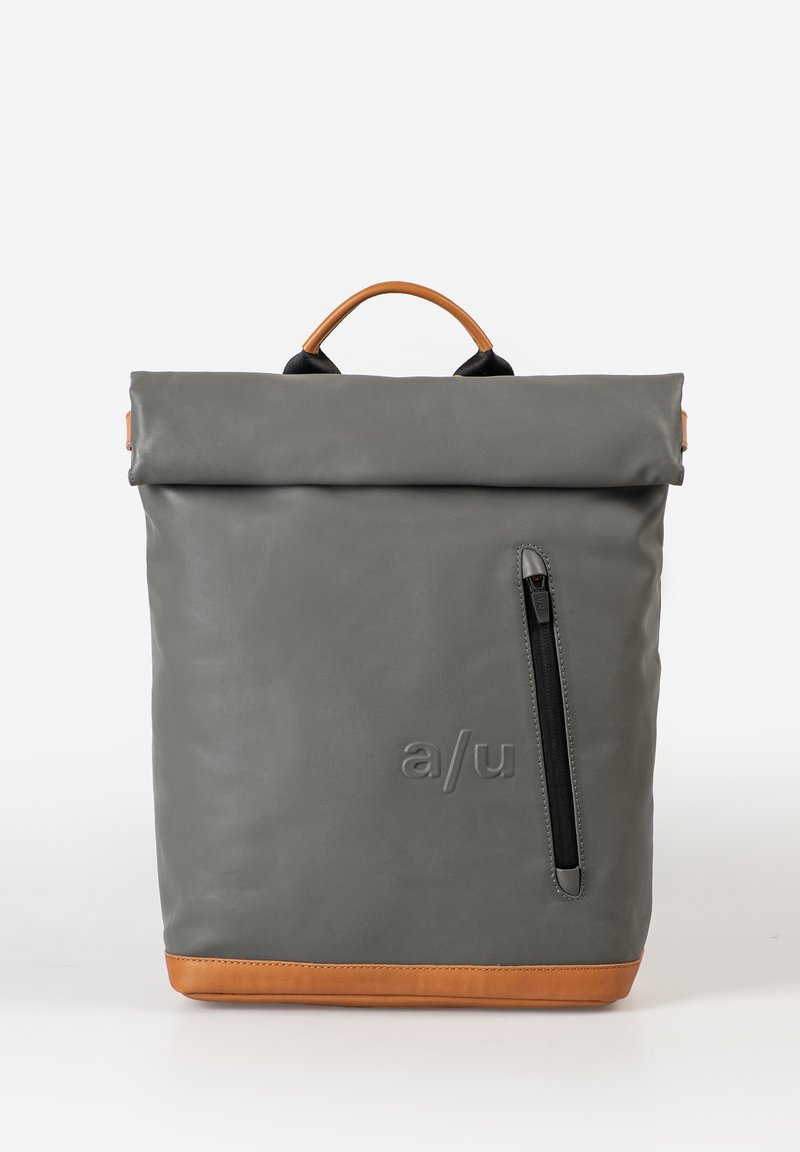 Gray roll-top backpack made of durable material with a brown leather bottom, features a side zipper pocket and a top handle for carrying.