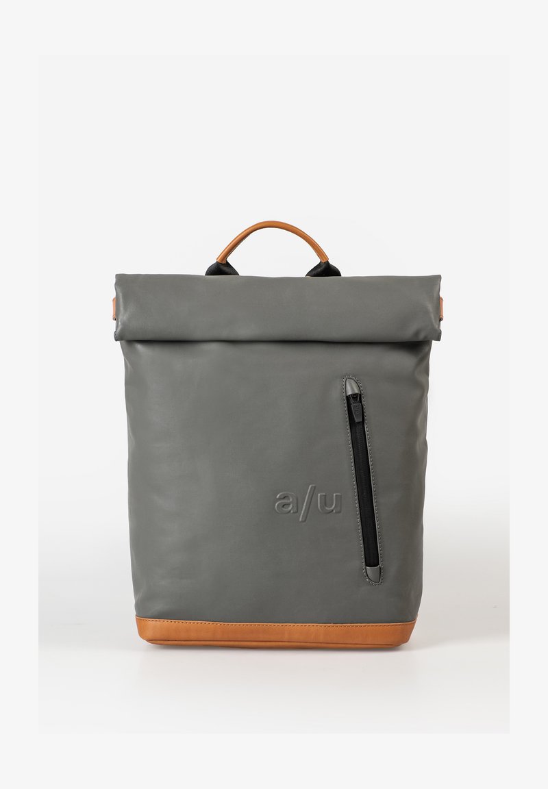 Grijze roll-top rugzak gemaakt van duurzaam materiaal met een bruine lederen bodem, voorzien van een zijrits zak en een handvat aan de bovenkant om te dragen.