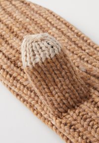 Calza a punta beige lavorata a maglia con filato texture, con punta arrotondata e corpo a coste. Il tessuto è spesso e accogliente, evidenziando l'artigianato.