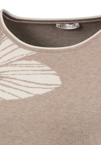 Beżowy sweter dzianinowy z okrągłym dekoltem, z dużym białym wzorem liścia po lewej stronie i jasnym wykończeniem.