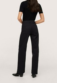 Pantalons noirs à taille haute et à jambes larges, en tissu structuré. Comprend deux poches à l'arrière, une texture lisse et des détails de couture subtils.