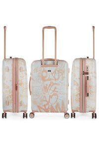 Maleta rígida con una base blanca que presenta patrones de estilo graffiti en tonos suaves de rosa. Acentos en color rosa dorado, dobles ruedas y asa retráctil.