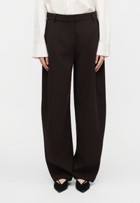 Μαύρο παντελόνι με φαρδύ πόδι από ελαφρύ ύφασμα, με λεία υφή, πιέτες μπροστά και προσαρμοσμένη ζώνη μέσης, συνδ υασμένο με μαύρα μυτερά παπούτσια.