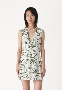 Floral-patterned dress in white and green, featuring a v-neck and sleeveless design. Made of lightweight fabric with a textured finish.