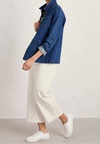 Džínová bunda v tmavě modré barvě, ohrnovací rukávy a přední knoflíky. V kombinaci s krémovými širokými kalhotami a bílými teniskami. Texturovaná tkanina.