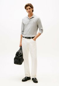 Polo a maniche lunghe grigio, pantaloni bianchi, cintura nera, borsa in pelle nera, scarpe lucide nere. Design semplice, texture liscia.