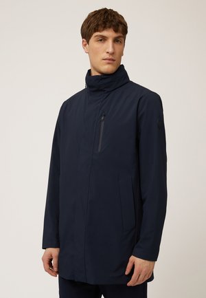 Marineblauwe waterdichte jas met een hoge kraag, een ritszak op de borst en twee zijzakken. Gladde textuur met een minimalistisch ontwerp.